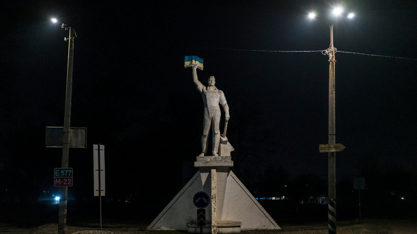 Sovyet döneminden kalan “Bilgi Kuvvettir” isimli heykel, şimdilerde bir Ukrayna bayrağını yükseltiyor (Fotoğraf: Brendan Hoffman/The New York Times)