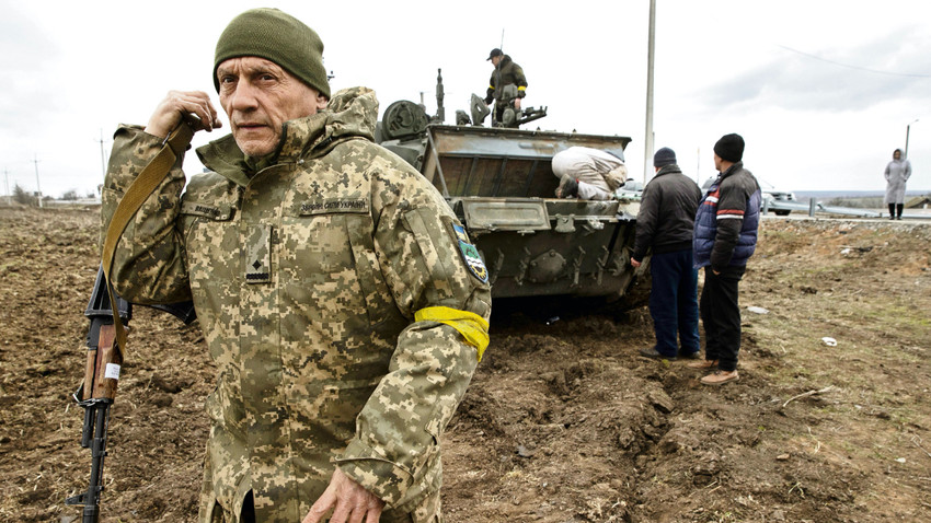 Mıkolayiv’de Ukraynalı köylüler kullanılmaz hale gelmiş bir Rus tankını çalıştırmaya çalışıyor (Fotoğraf: Tyler HIcks/The New York Times)