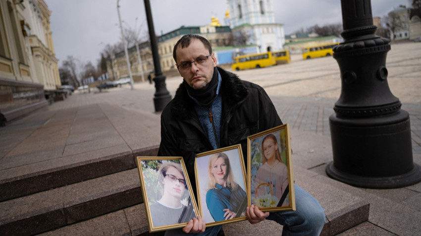 Serhiy Perebeyinis, öldürülen ailesinin portrelerini tutuyor. (Fotoğraf: Lynsey Addario/The New York Times)