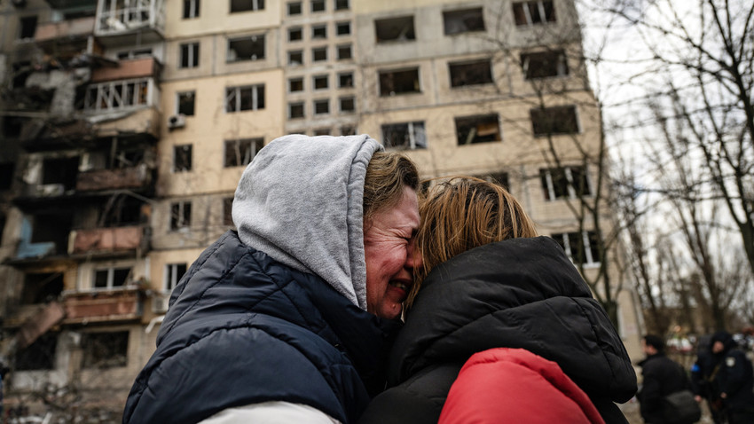 Kiev'in Obolon bölgesinde apartmanı vurulan sakinler, eşyalarını kurtardıktan sonra birbirine sarılıyor. 14 Mart 2022 (Fotoğraf: Lynsey Addario/The New York Times)
