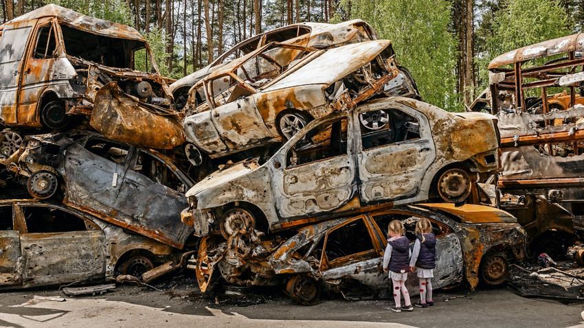 Kiev yakınlarındaki Irpin’de çocuklar harap olan araçlara bakıyor (Fotoğraf: Daniel Berehulak/The New York Times)