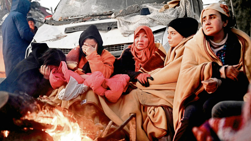 Depremin üçüncü gününde enkazların yanında ısınmaya çalışan Kahramanmaraşlılar. (Fotoğraf: Ozan Köse /AFP Via Getty  Images)