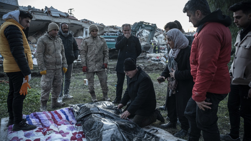 8 Şubat'ta Antakya'da bir enkazdan çıkarılan bir cesedin etrafında toplanan aile üyeleri (Sergey Ponomarev/New York Times)