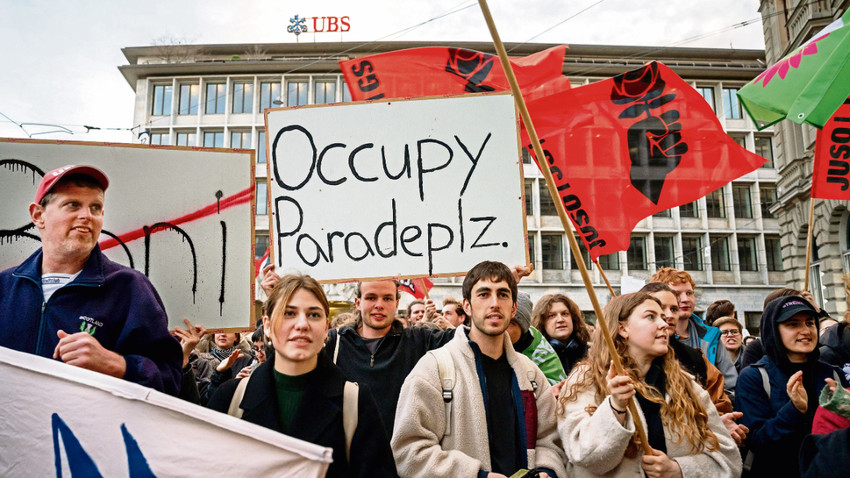 UBS’in Credit Suisse’i devralma kararının ardından Genç Sosyalistler Partisi üyeleri iki bankanın Zürih’teki binalarının önünde. (Fotoğraf:  AFP vIa Getty Images)