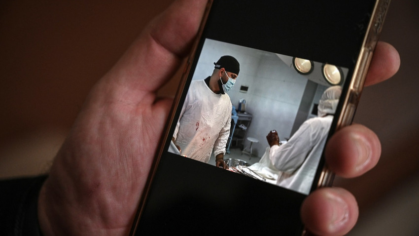 Dr. Samer al-Sheikh Londra'daki evinde telefonunda Ukrayna'da yaptığı cerrahi çalışmaların fotoğraflarını gösteriyor (Fotoğraf: Mary Turner/The New York Times)