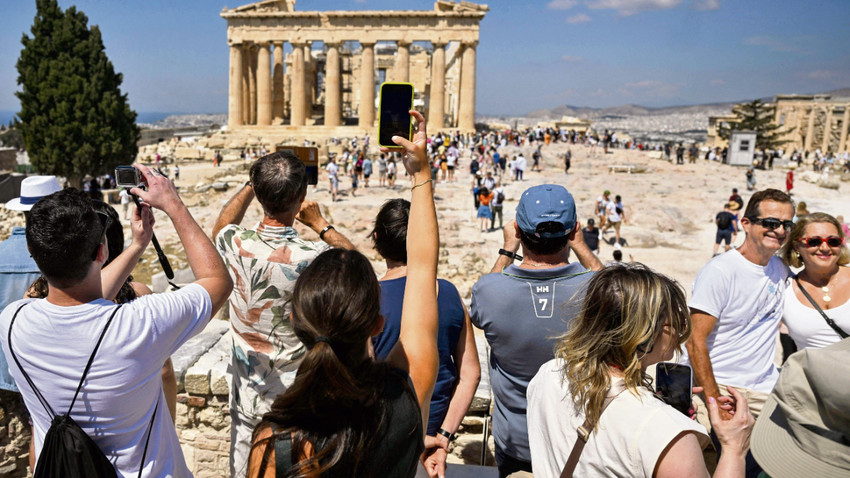 Atina'daki Akropolis’te bulunan Parthenon Tapınağı önünde fotoğraf çeken turistler.