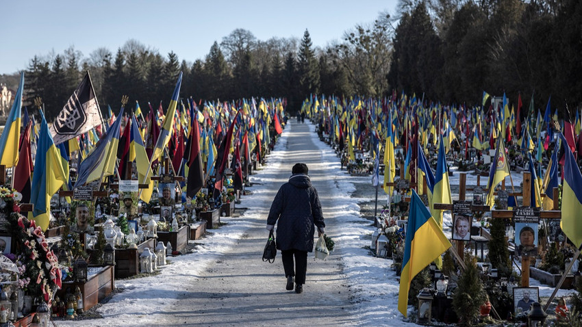 Rusya'nın Şubat 2022'de ülkeyi tamamen işgal etmesinden bu yana çatışmalarda ölen Ukraynalı askerlerin mezarları arasında yürüyen bir kadın, 30 Ocak 2024 (Fotoğraf: Finbarr O'Reilly/The New York Times)