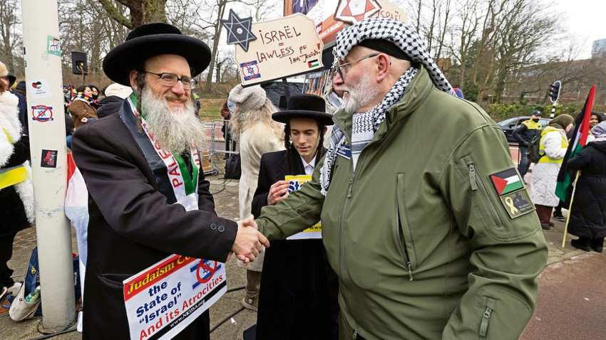 Lahey’deki Uluslararası Adalet Divanı önünde İsrail’i protesto eden bir kişi kendisine destek veren bir ultra-Ortodoks Yahudi ile tokalaşıyor. (Getty Images)