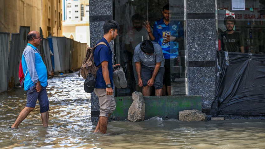 17 Nisan 2024'te Dubai Sharjah'da şiddetli yağışların ardından insanlar sular altında kalan caddede yürüyor. (Fotoğraf: AHMED RAMAZAN/AFP, Getty Images)