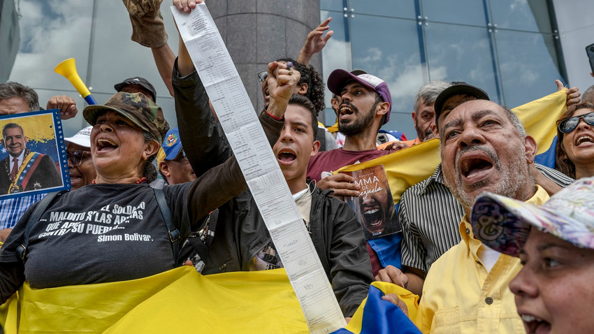 Muhalefet lideri Maria Corina Machado ve başkan adayı Edmundo Gonzales'in Caracas'ta düzenlediği miting sırasında bir gösterici elinde oy verme makinesi tarafından sayılan toplam oyların listesini tutuyor (Fotoğraf: Alejandro Cegarra/NYT)