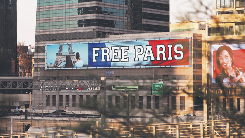 Macron’un kararının ardından Tel Aviv’deki ekranlara “Paris’i özgürleştirin” yazılı görseller yansıtıldı. Fotoğrafta Eyfel Kulesi önünde başörtülü bir kadının da durduğu görülüyor.
