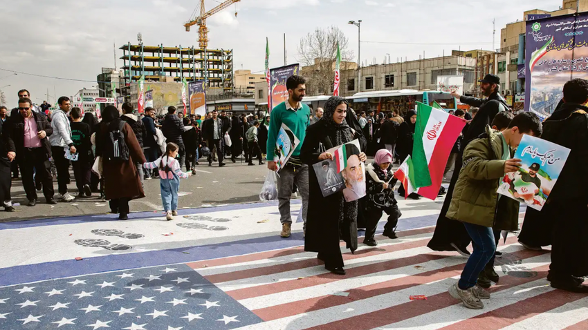 Tahran’da Trump’ın tehditlerinden sonra İslam Devrimi’nin yıl dönümünde insanlar Amerikan ve İsrail bayraklarının üzerinde yürüdü. (Fotoğraf: Arash Khamooshi /The New York Times)