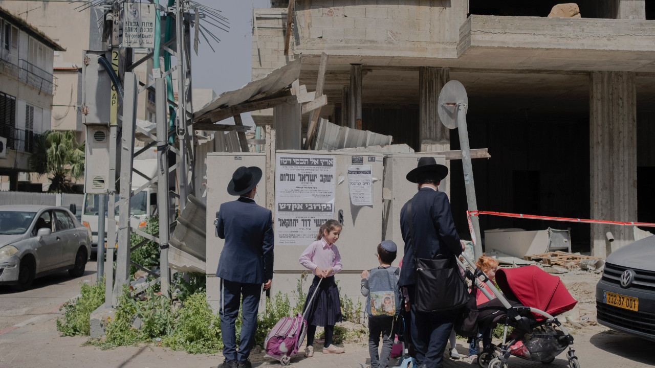 Bnei Brak'ta gerçekleşen saldırı sonrası ölüm ilanını okuyan insanlar. 30 Mart 2022 (Fotoğraf: Amit Elkayam/The New York Times)