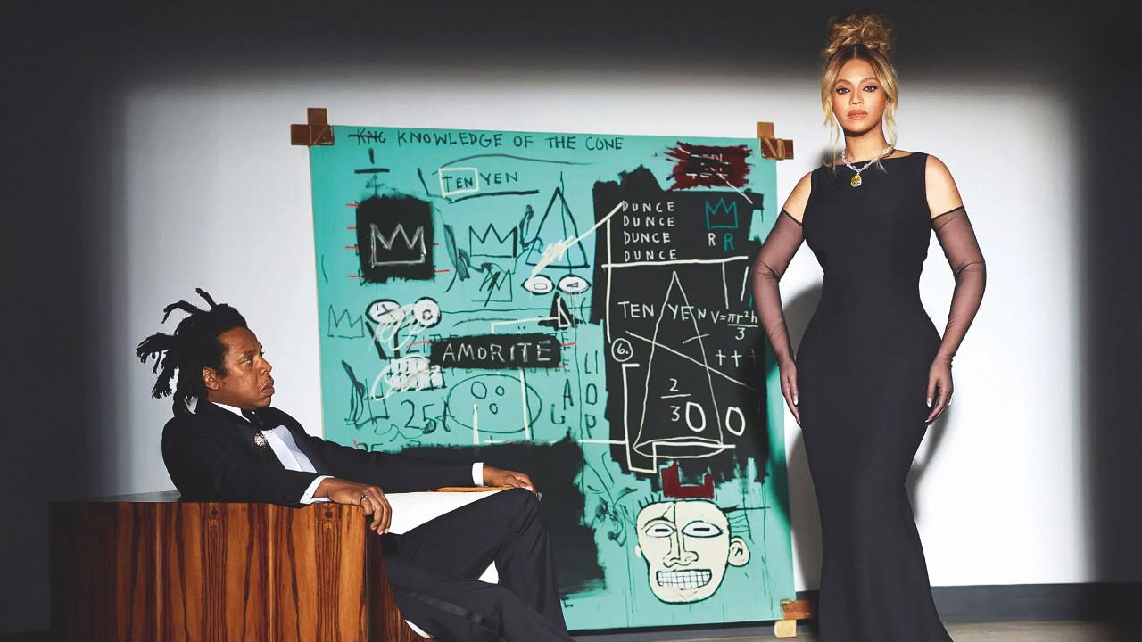 Arka planda Basquiat’nın Equals Pi adlı tablosu. Tiffany&Co’nun yeni yüzü Beyonce, boynunda ünlü Tiffany sarı elmasıyla görünüyor. Bir sonraki sahnede Moon River şarkısını söylerken eşi Jay-Z ile birlikte pizza atıştıracaklar